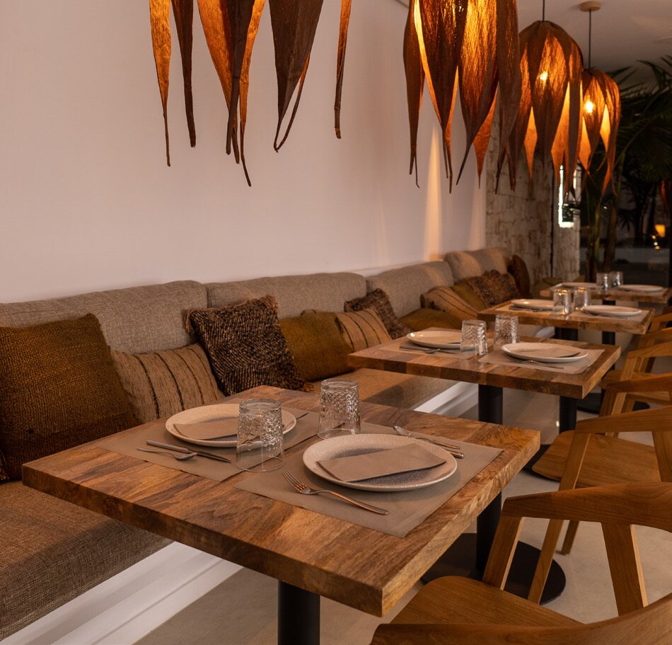 Salle à manger chaleureuse, tables de bois et lampes tressées